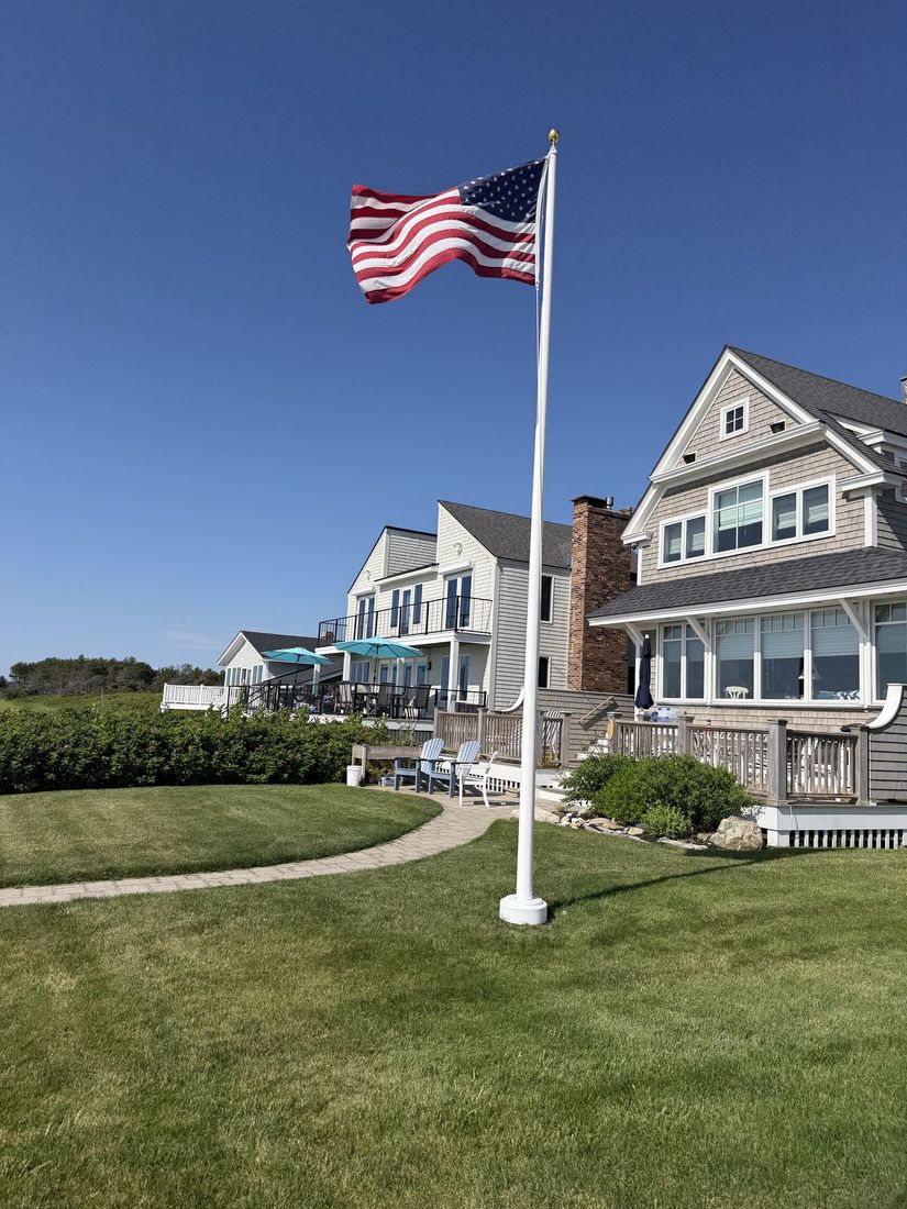 White fiberglass flagpole installed on the lawn of a coastal Maine home
