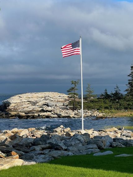 Flagpole on a granite ledge above the water on the Maine coast