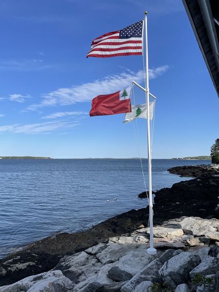 American and Maine flags flying above a rocky shoreline