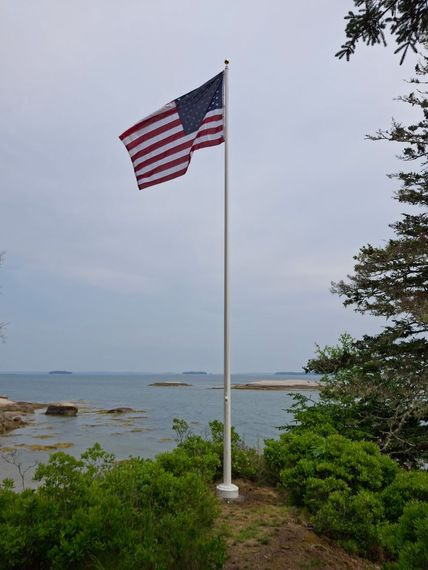 White flagpole overlooking the open ocean from a wooded point