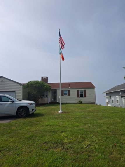 Residential flagpole on a lawn beside a Maine ranch home