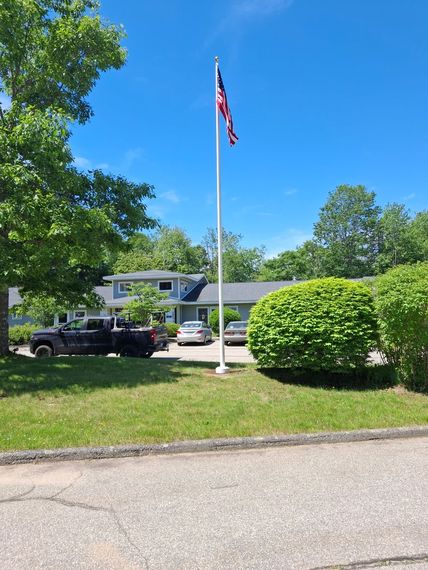 Newly installed residential flagpole beside a driveway