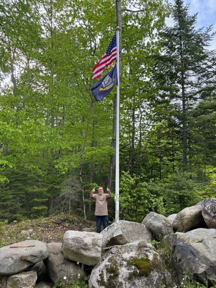Customer beside a newly installed flagpole set into a stone outcrop
